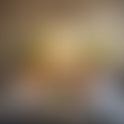 An out of focus photo of a team around a table in an office. With a lightbulb in focus in the foreground.