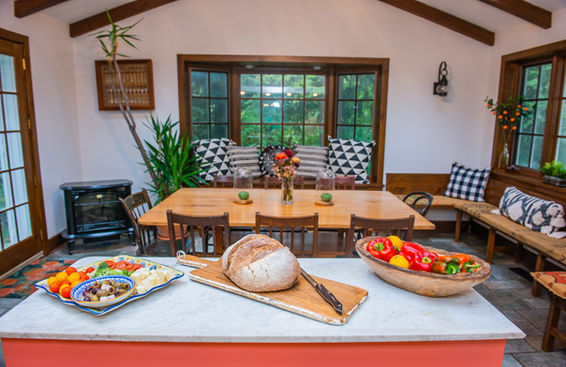 Kitchen with table and chairs and an island with bread and vegetables laid out
