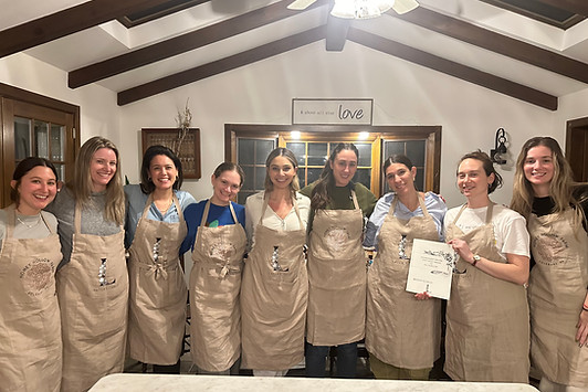 Group of women wearing brown aprons standing in a kitchen