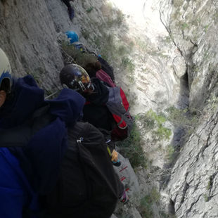 happy lady smiling at the camera as she is doing via ferrata holding the iron safety cable