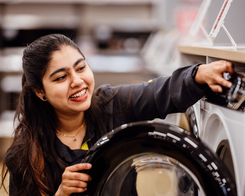 Smiling woman holding the door of a washing machine Careers In Store – Learning and Development