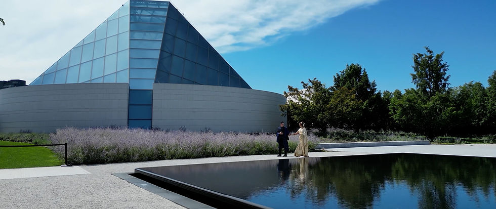 Bride and groom walk beside the reflecting pool at the Aga Khan Museum in Toronto, framed by contemporary architecture and lavender bushes.
