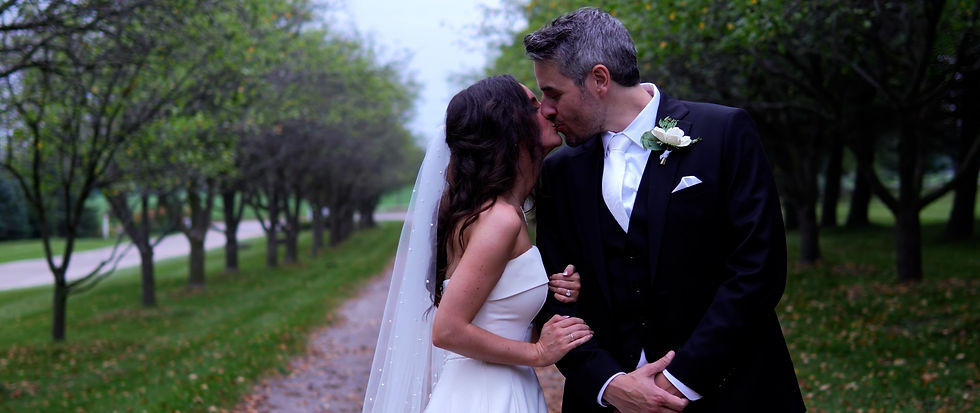 Bride and groom share a quiet embrace at their candlelit reception space at Elora Mill, surrounded by elegant white florals and long banquet tables set for dinner.