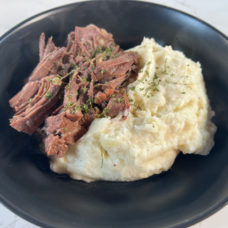 a bowl filled with shredded pot roast alongside creamy mashed potatoes