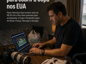 Fotógrafo esportivo editando imagens em um quarto simples, com câmera profissional, credencial de imprensa e camisa do Santos sobre a mesa.