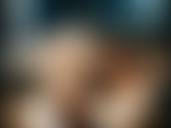 Fotografia editorial em close-up das mãos de um fotógrafo experiente segurando um retrato impresso em papel texturizado sobre uma mesa de luz, usando uma lupa de contato. Ao fundo, levemente desfocadas, telas de computador modernas exibem interfaces complexas de edição digital, ilustrando o contraste entre a curadoria humana tátil e o fluxo de trabalho tecnológico no bastidor.