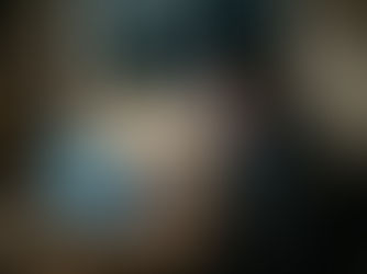 Fotógrafa trabalhando tarde da noite editando fotos no laptop, cercada por equipamentos e papéis em uma mesa desorganizada, representando os desafios reais de viver da fotografia.