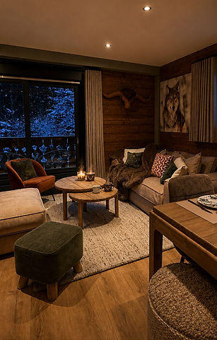 Salon chaleureux d'un chalet avec canapé, bois et vue enneigée.