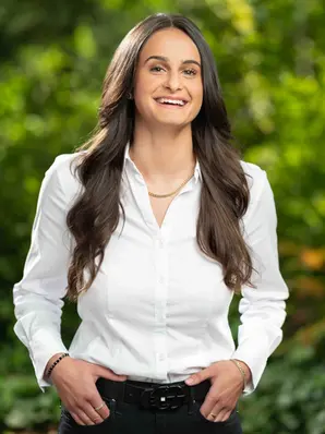Eine junge Mitarbeiterin eines Unternehmens mit weißer Bluse vor unscharfen Bäumen im Hintergrund in Hannover im Portraitfoto