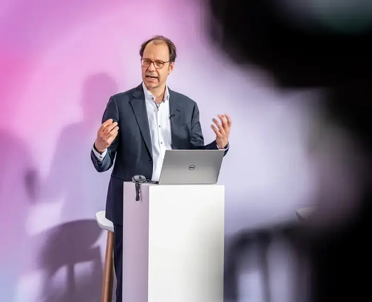 Ein Referent auf einer Bühne gestikuliert während seiner Keynote.