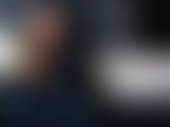 L'immagine ritrae lo stilista Giorgio Armani seduto su un divano, mentre sorride ed è vestito di blu, il suo colore preferito