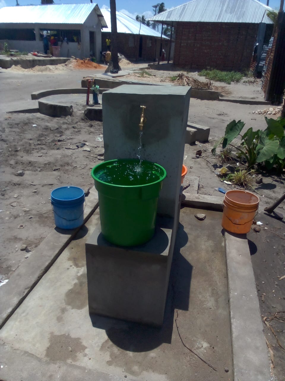 Water flowing at a community tap point in Palma District, fed by gravity from an elevated storage tank.