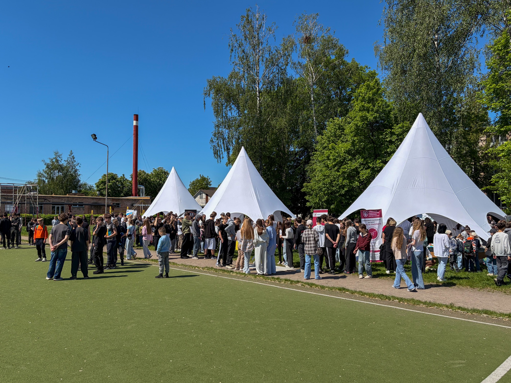 Students gather beneath white event tents at the Green Communities eco-festival in Kovel, Ukraine