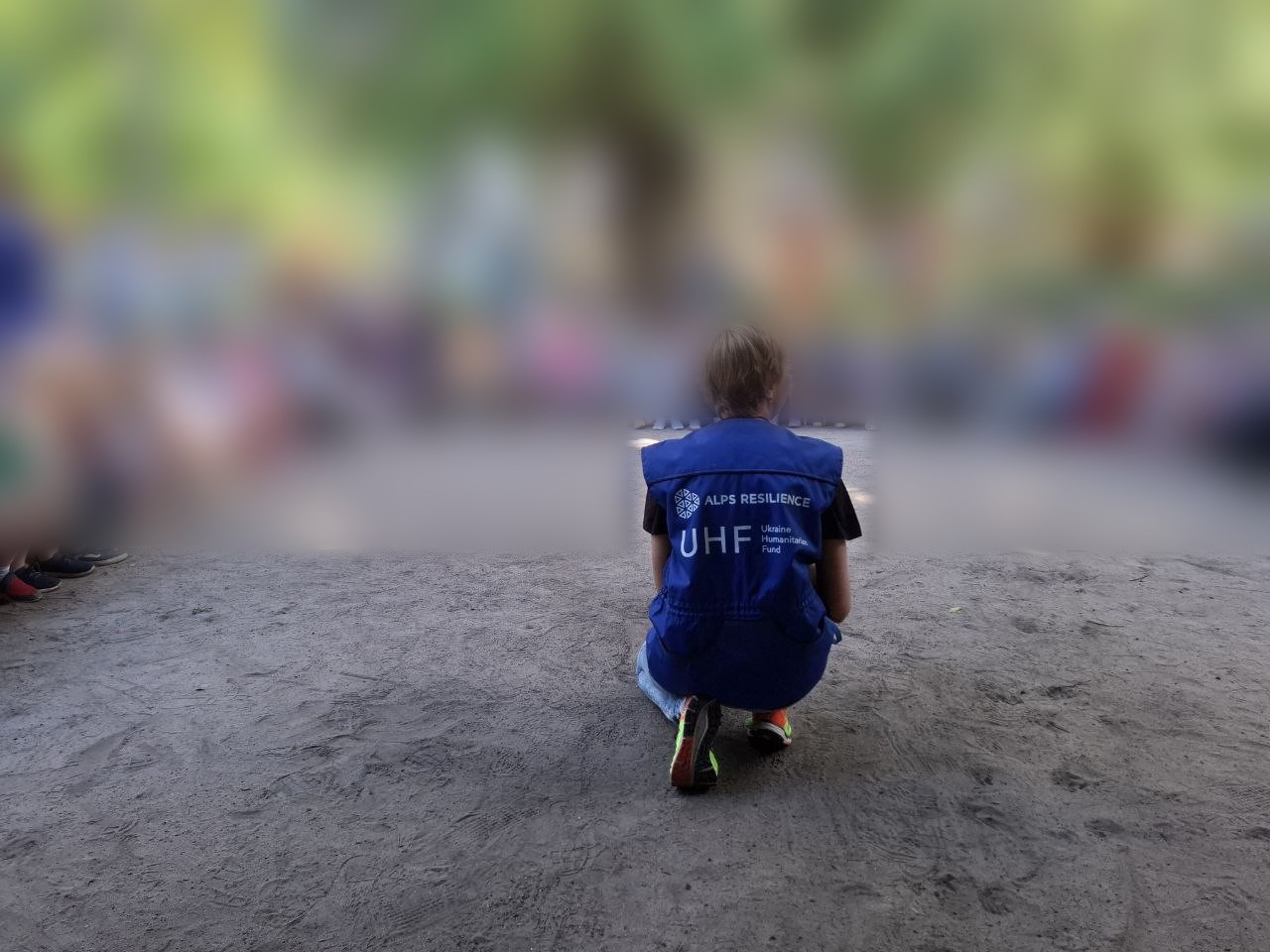 A therapy handler in an ALPS Resilience and Ukraine Humanitarian Fund vest in front of a circle of children, faces blurred
