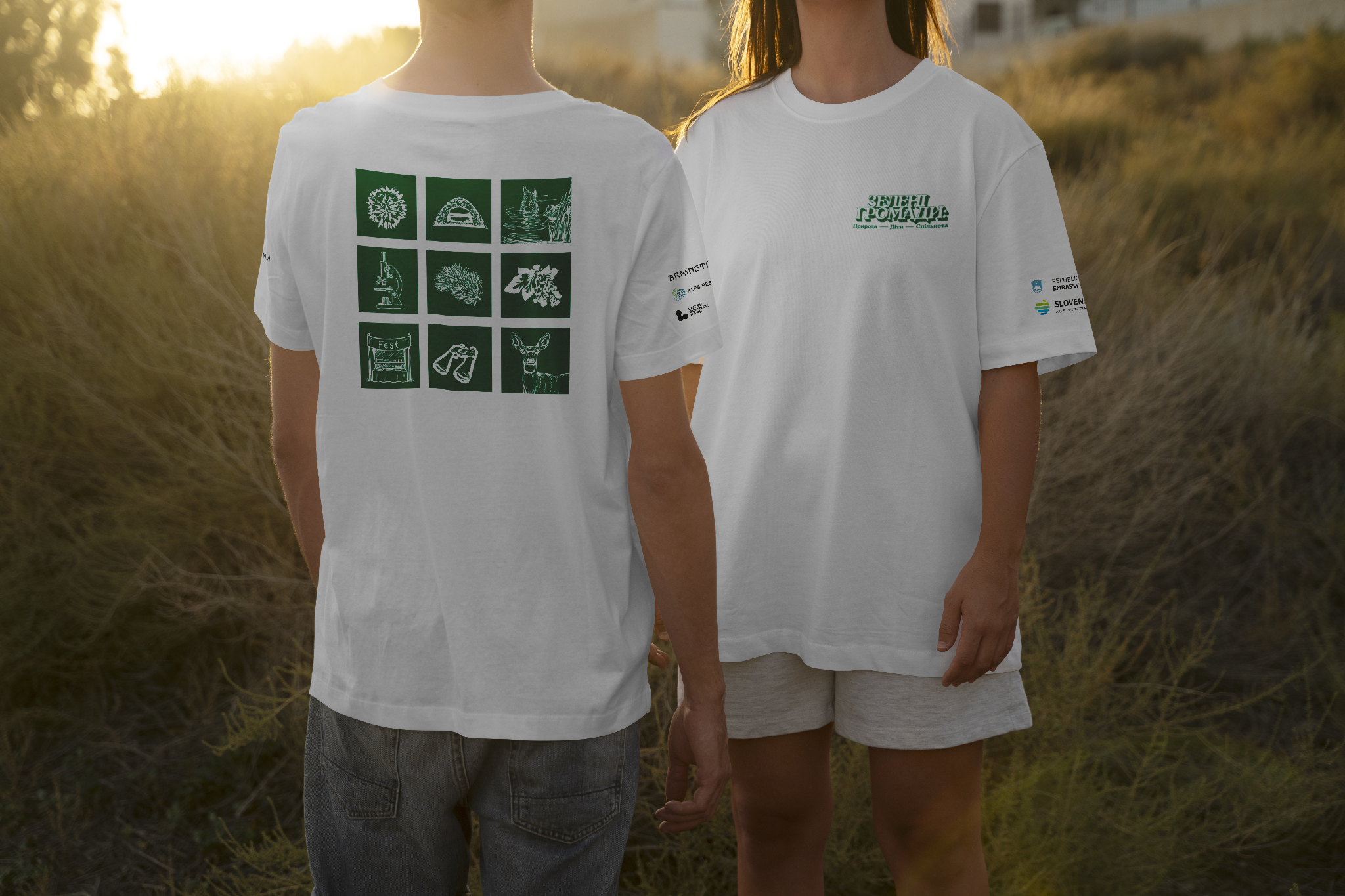 Two students seen from behind wearing white Green Communities project T-shirts