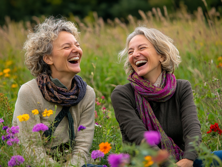 Two woman laughing while sitting on a prairie.