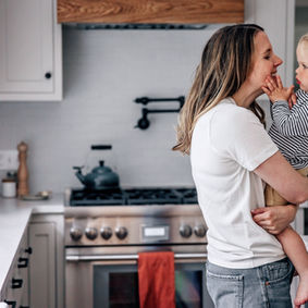 a mom holding her daughter in the kitchen during an in home docutmentary in home storytelling session in Wellesley MA