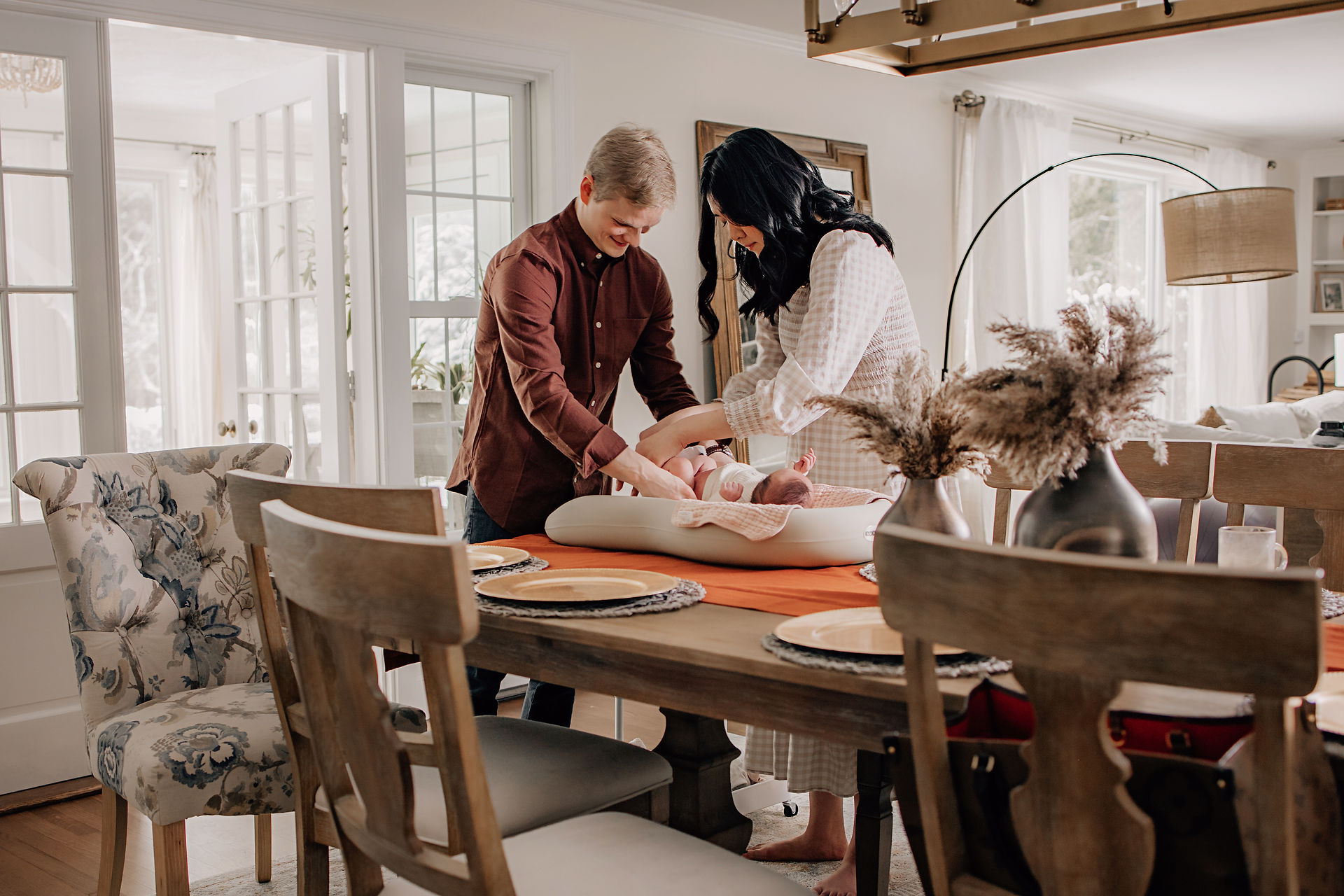 Parents changing their newborn together on a table during an in-home newborn photography session