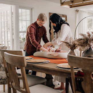Parents changing their newborn together on a table during an in-home newborn photography session
