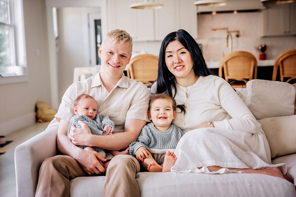 Family on couch. New parents holding newborn with their little girl during an in home newborn session