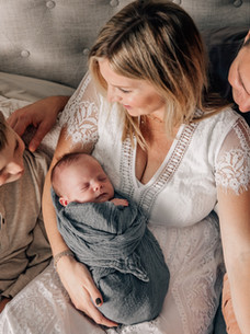 Family cuddling newborn together during an in-home newborn photography session near Westwood, MA