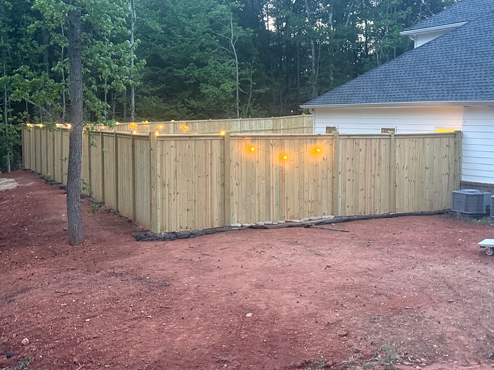 Wooden privacy fence installation with string lights.
