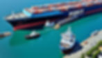 A ship being towed into port by tugboats.