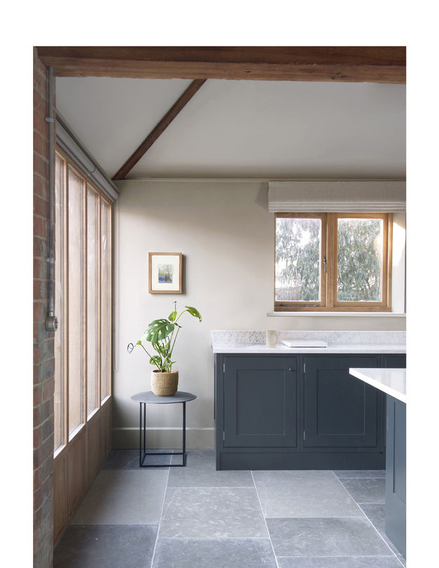 A shaker kitchen with oak-framed windows and marble worktops