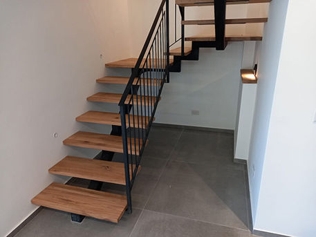 מדרגות עץ אלון מלא עם מעקה ברזל שחור בעיצוב מיוחד ובטיחותי -זווית, תכנון מדרגות ובניית מדרגות מעוצבות.