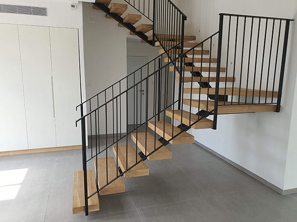 מדרגות עץ מעוצבות עם מעקה ברזל שחור, מעקה בטיחותי למדרגות פנים.
