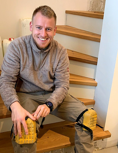 Ich bei der Montage von Treppenstufen aus Eiche. Eine Momentaufnahme in der ich mir gerade den Knieschutz anziehe.