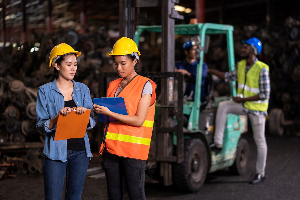 Engineer woman wearing helmet standing at the large warehouse where keep automotive parts