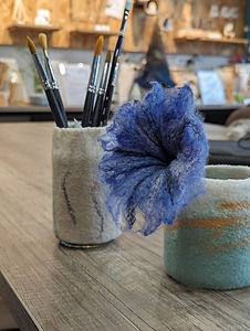 2 caches pots de tailles différentes adaptés sur des bocaux du commerce, l'un avec des pinceaux dedans, un autre avec une fleur feutrée