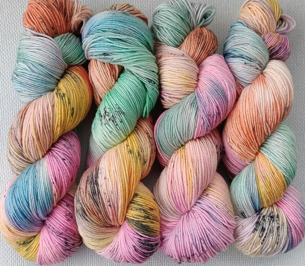 Hand dyed yarn hank in pinks, yellows, blues, lilacs, rust, & mint with black speckles