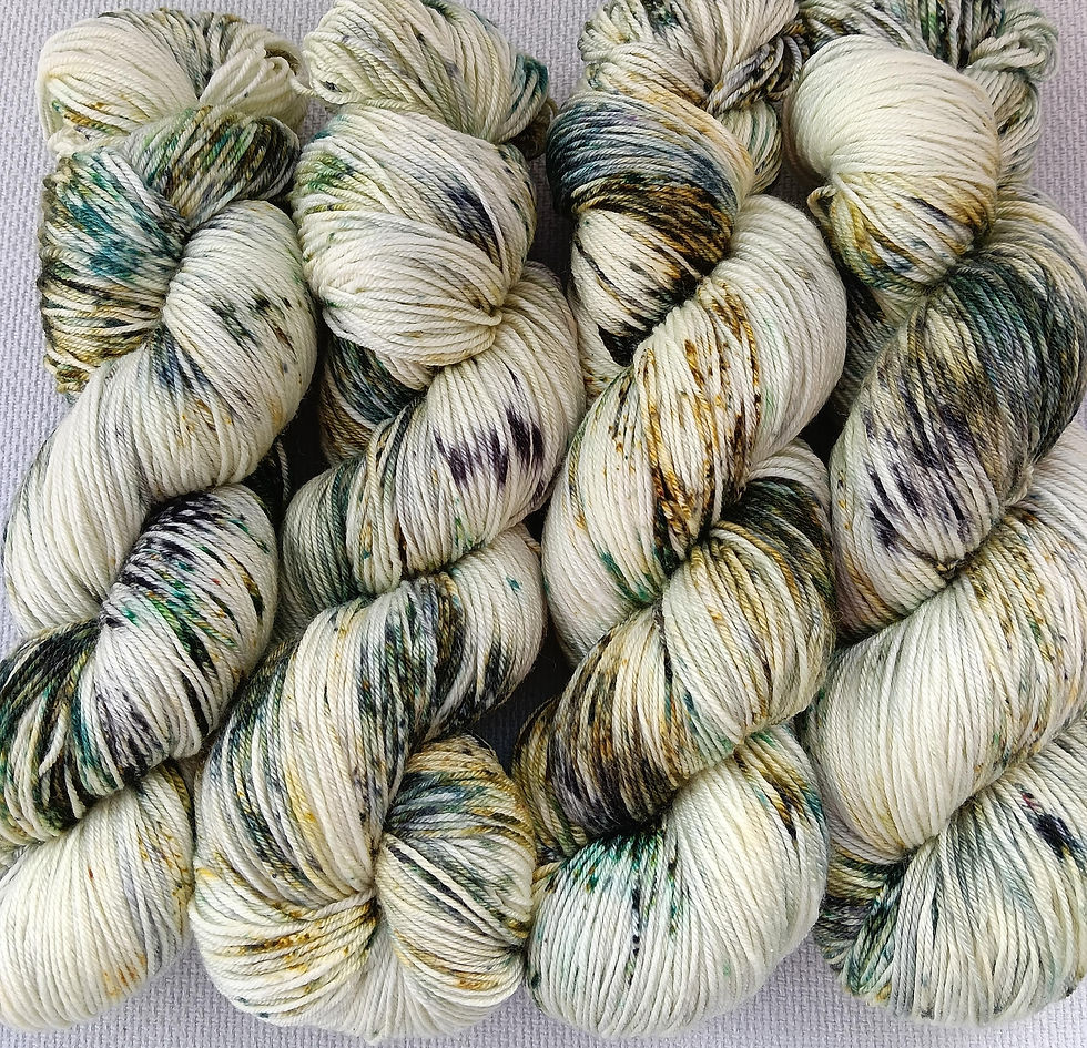 Hand dyed hanks of yarn with a cream background and lots of different greens dye speckles called Snow Bark.