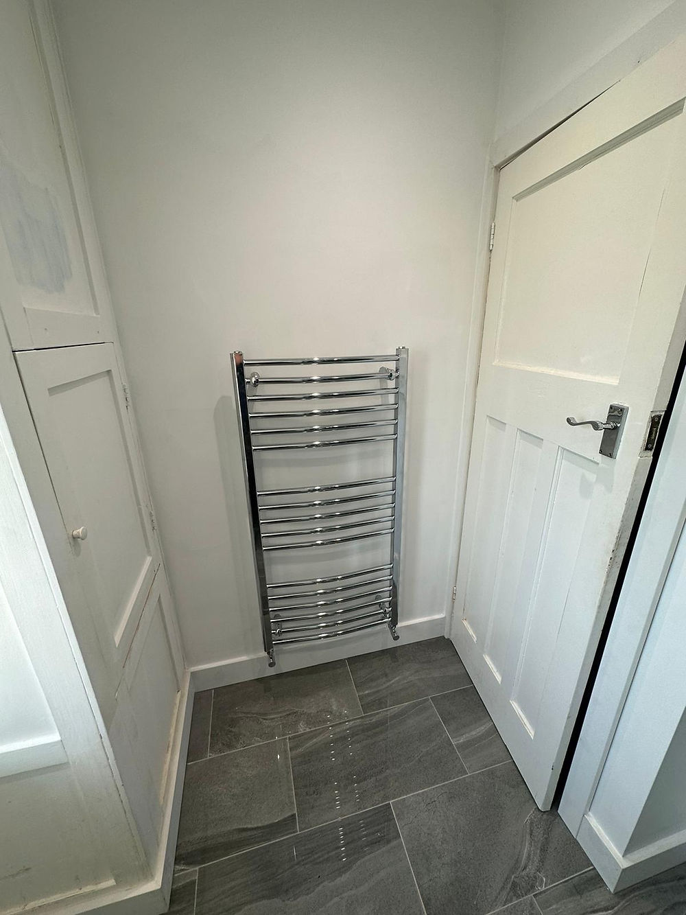 Modern chrome heated towel rail installation, part of a full bathroom maintenance contract in Worcestershire.