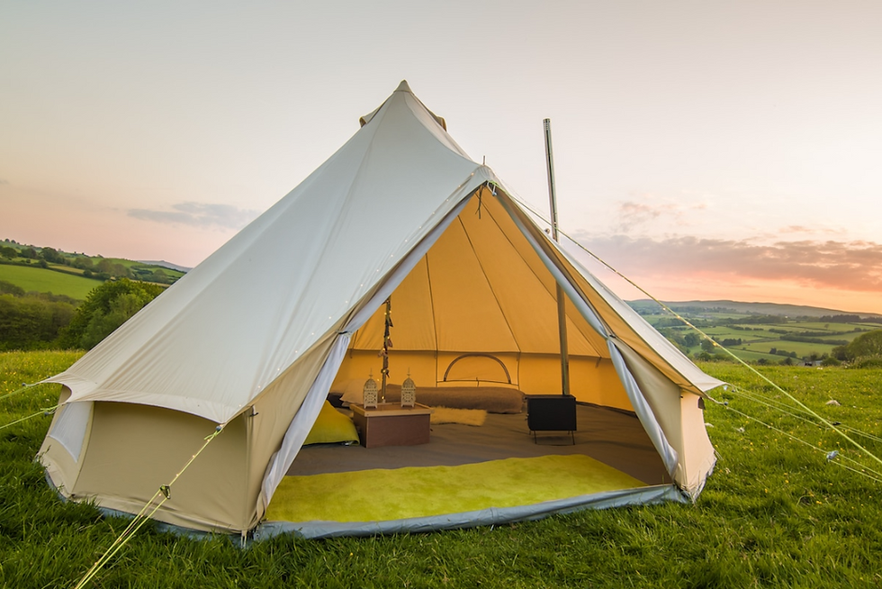 Canvas bell tent, with door tied back revealing spacious interior with rug, bed and stove