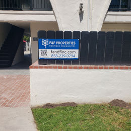 blue and white sign made for an apartment and installed on fence in La Mesa