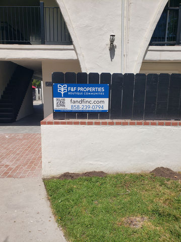 blue and white sign made for an apartment and installed on fence.