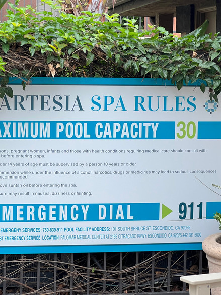blue and white spa rules sign installed on fence with vines in san diego.