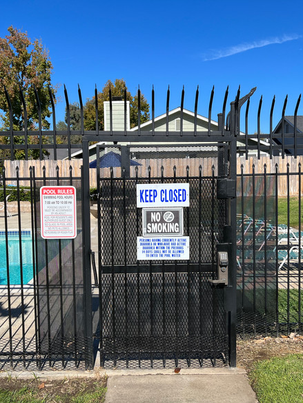 black gate with white and blue  pool rules and keep closed signs