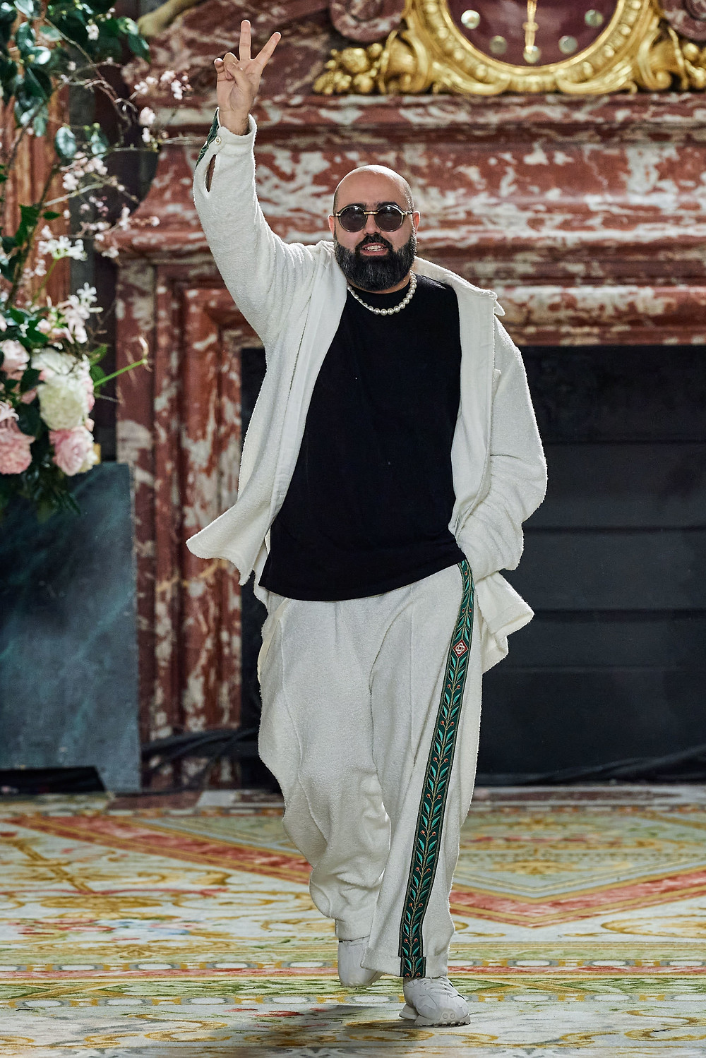 On the runway, Tajer wears sweatsuit he designed while flashing the peace sign