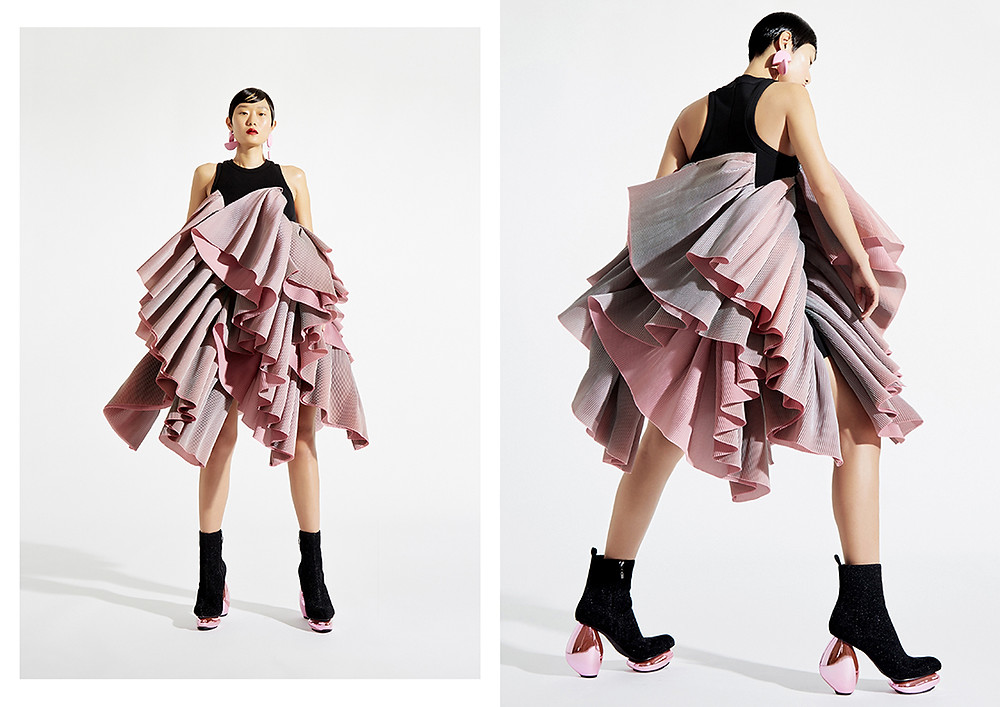 A model wears a black and pink, flowy design by Wun, also featuring several layers of fabric to create a dramatic skirt