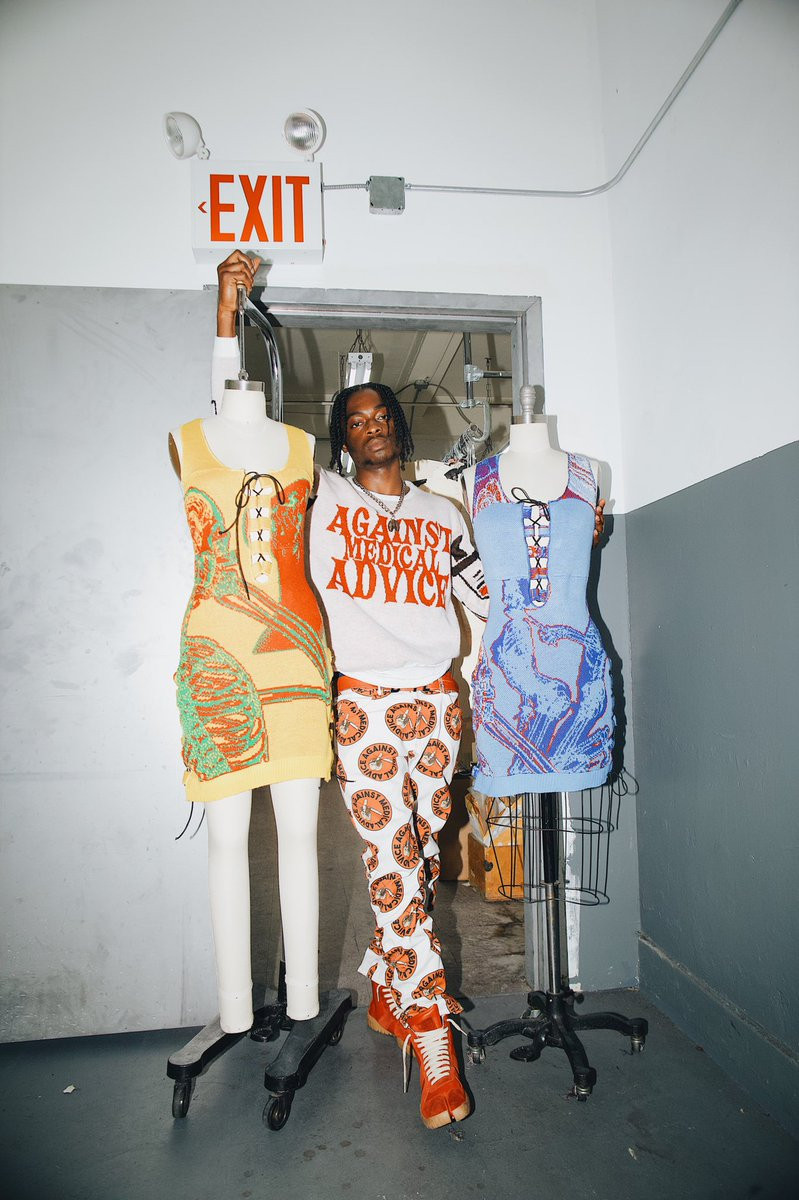 Olosunde poses with two mannequins fitted with skeleton-bearing dresses