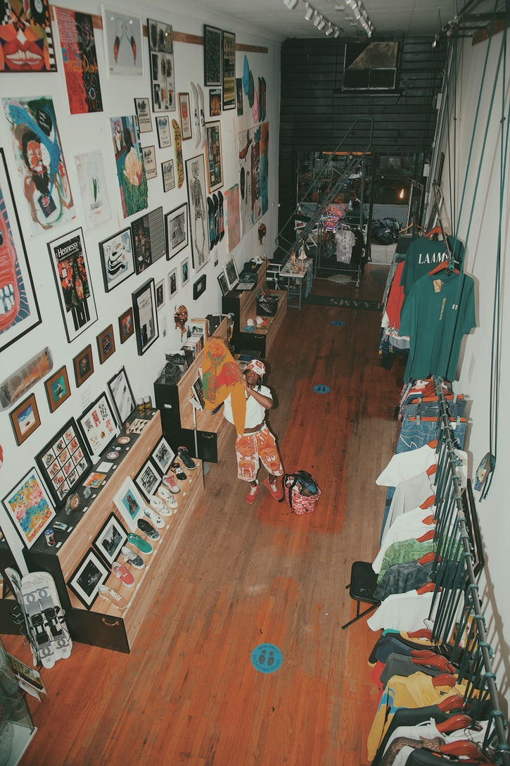 Olosunde stands in a warehouse, studio space, holding his designs up to the camera