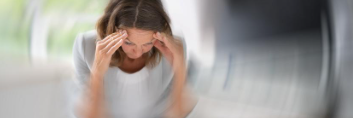 A woman experiencing post-concussion symptoms (dizziness, headache, brain fog)