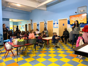 A vibrant preschool setting with young children seated at small tables, engaged in an interactive learning session at TYL II Preschool & Childcare.