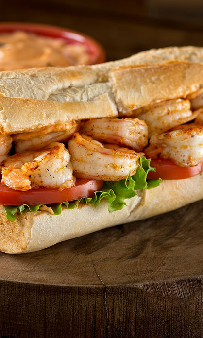 A delicious home made grilled shrimp Po Boy sandwich on baguette dressed with lettuce, tom