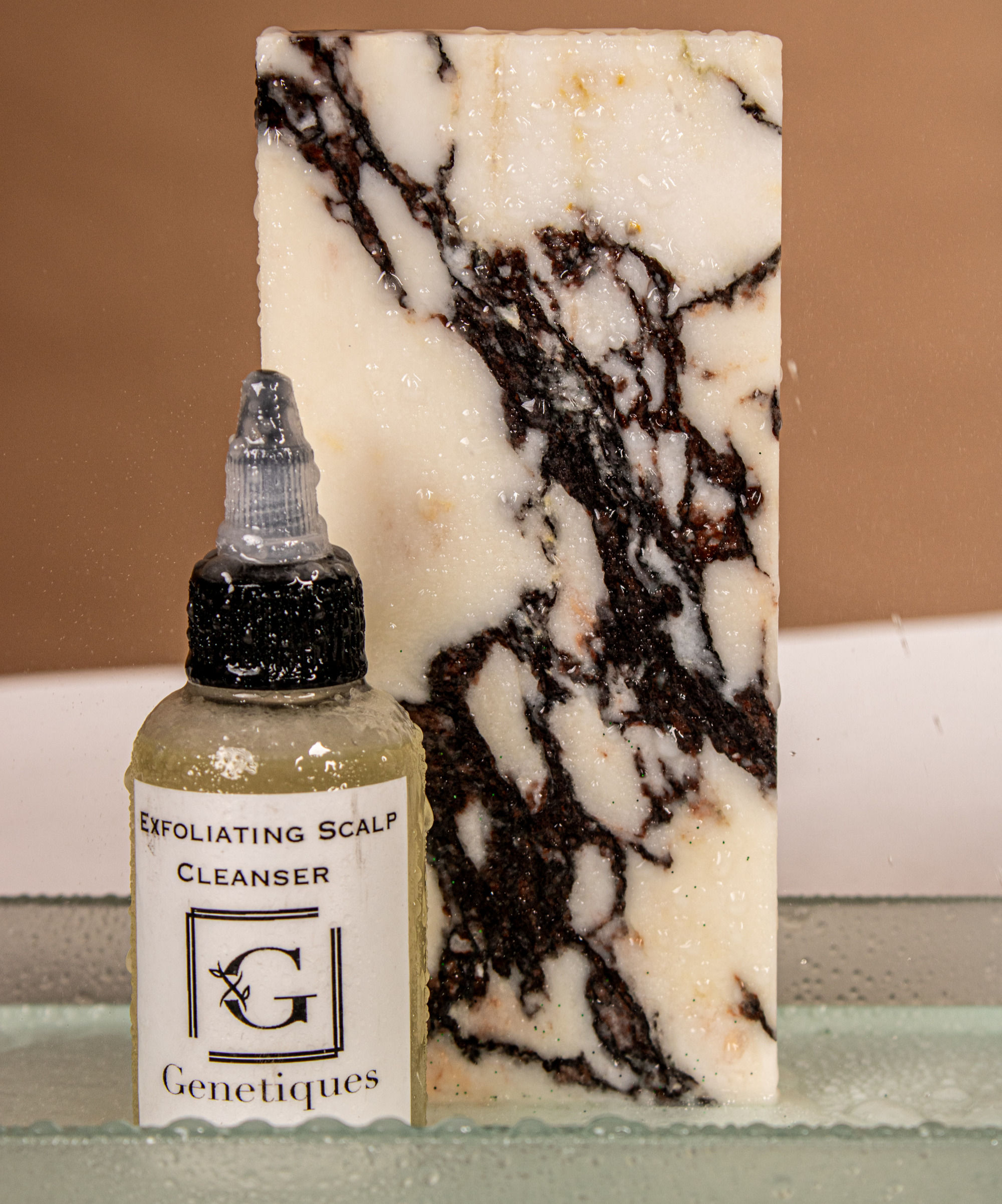 Exfoliating Scalp Cleanser, Genetiques bottle with a marble background. Cleanser label visible