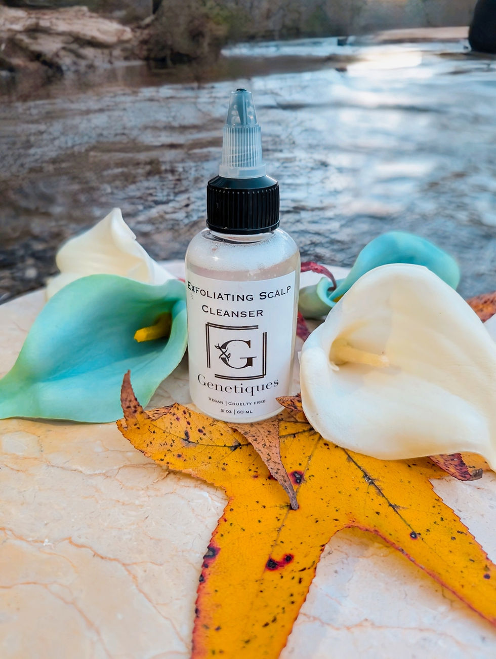 Thumbnail: Bottle of Scalp Cleanser, Genetiques Hair and Beauty, with white flowers and fall leaves.